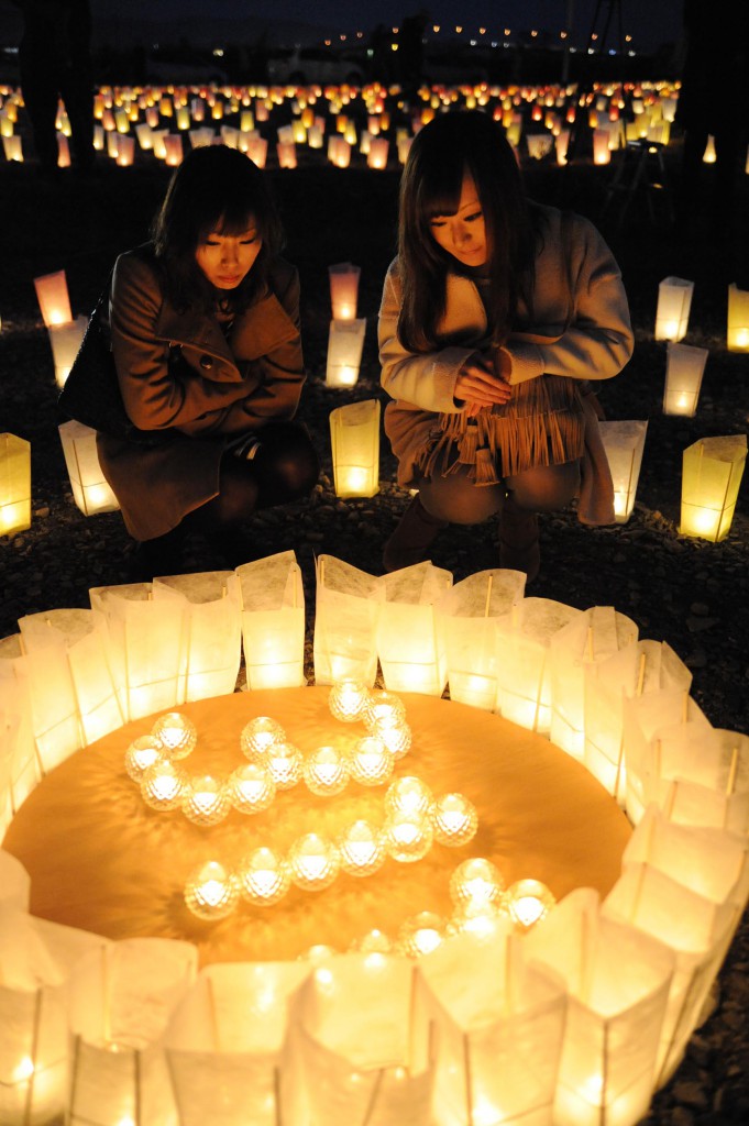 Women sit beside the lit lanterns to think of the victims of tsunami in Ishinomaki, Miyagi Prefecture on Thursday, December 5.