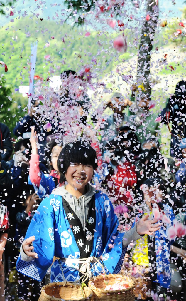Girl with great big smile in shower of flowers in Yoneyama Yakushido Shrine.