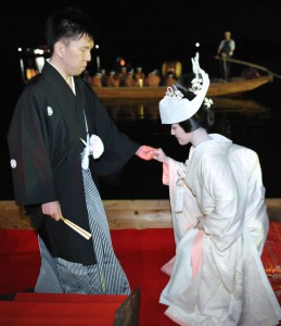 Groom escorting his bride on dock, gently holding her hand.