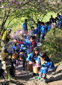 Children scatter flowers as they walk the path toward Yakushido Shrine.