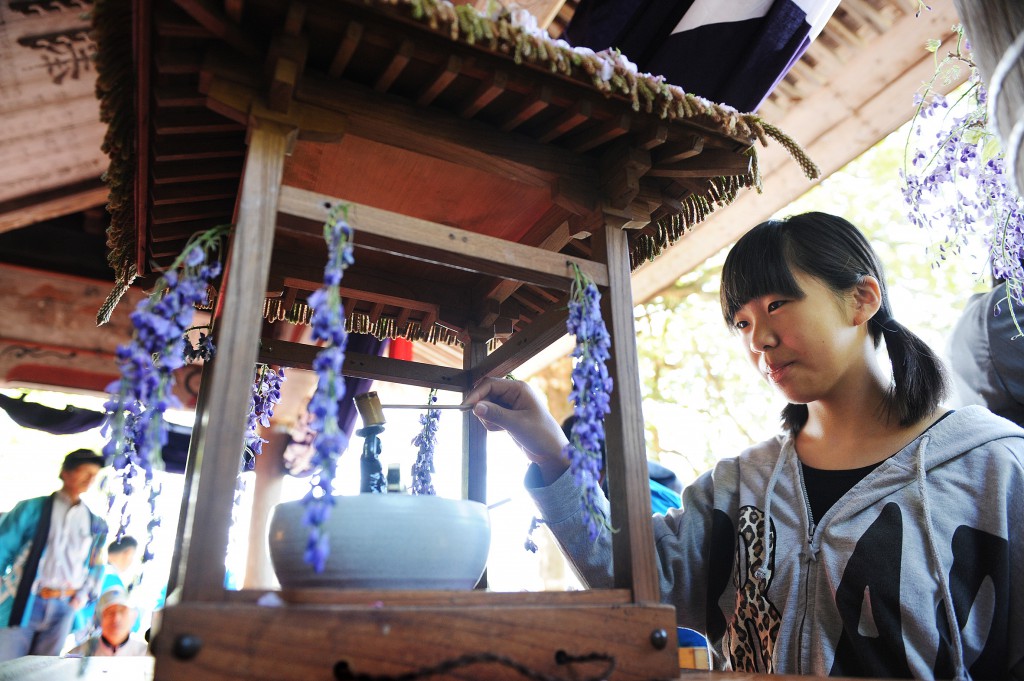 Children pour Ama-cha hydrangea tea over a small Buddha statue placed in the middle of the portable shrine.