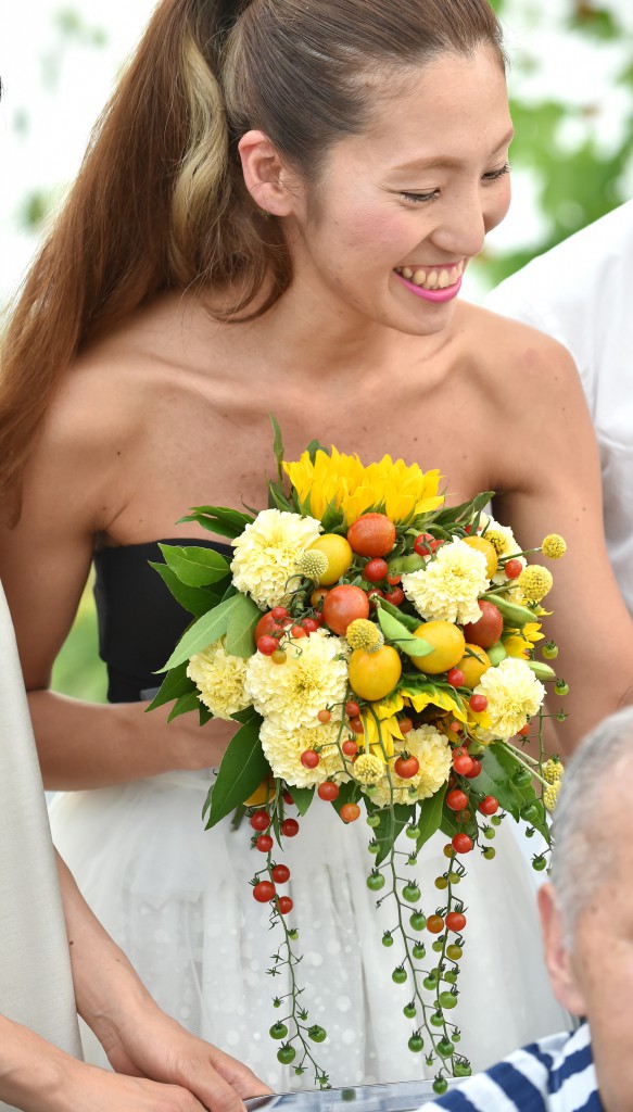 Hiromi Tokumoto, bride, with bouquet of sunflowers and grape tomatoes in different colors and sizes in hand 