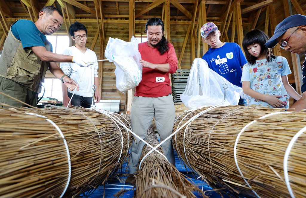 Professional adventurer, Jin Ishikawa, instructing boat building processes. Five parts are joined together by ropes to make boat.