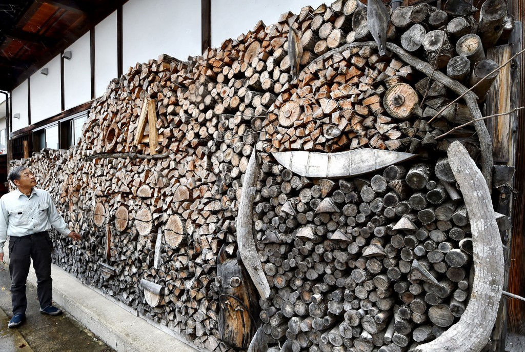 Tsukida creates woodpile mosaic under shallow eaves, using natural shapes of firewood. (in Minamiaizu-cho, Fukushima Prefecture) 