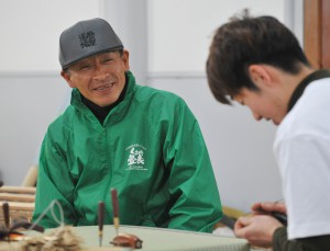 Shingo Kojima, General Manager of Yatsushiro Central Rush Grass Producers Group of JA, observing artisan’s work while having pleasant chat