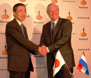 Norinchukin President and CEO Yoshio Kono (left) and Rabobank Executive Board member Berry Marttin shake hands at a press conference on Wednesday, May 27, in Tokyo after announcing the banks’ strategic alliance.