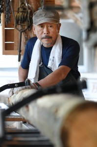 Yamada hand-cutting log into boards. He does everything from barking to lumbering.