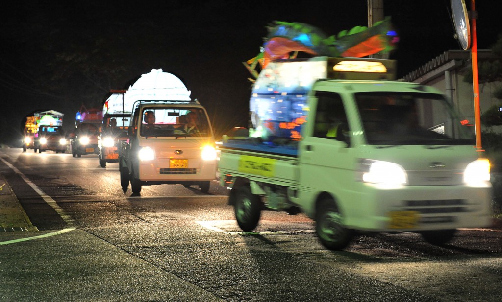 Pickup trucks with illuminated lanterns paraded down the roads at night
